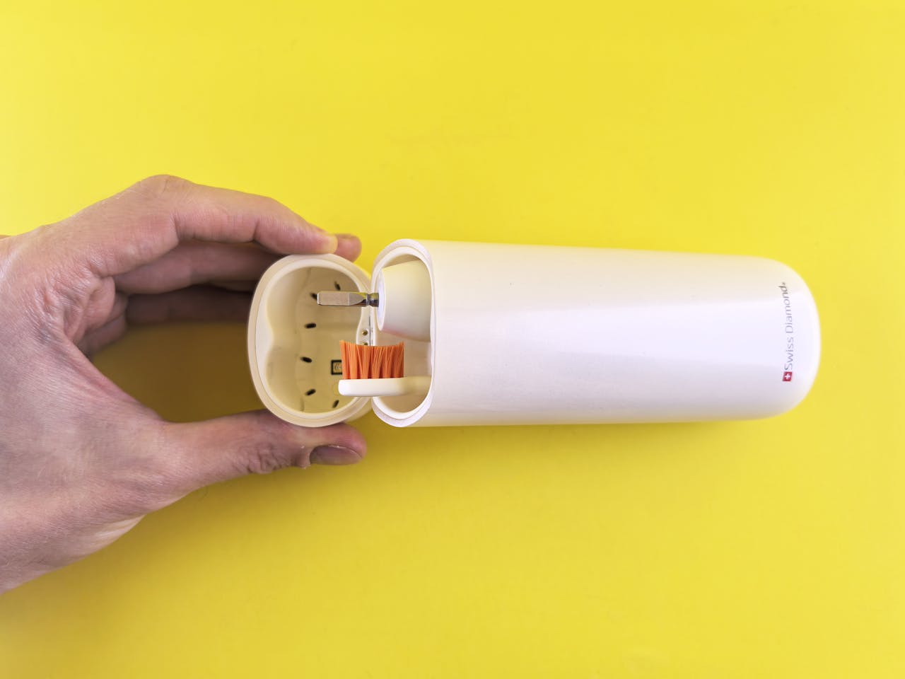 A stylish portable electric toothbrush with a sleek protective case against a vibrant yellow backdrop.