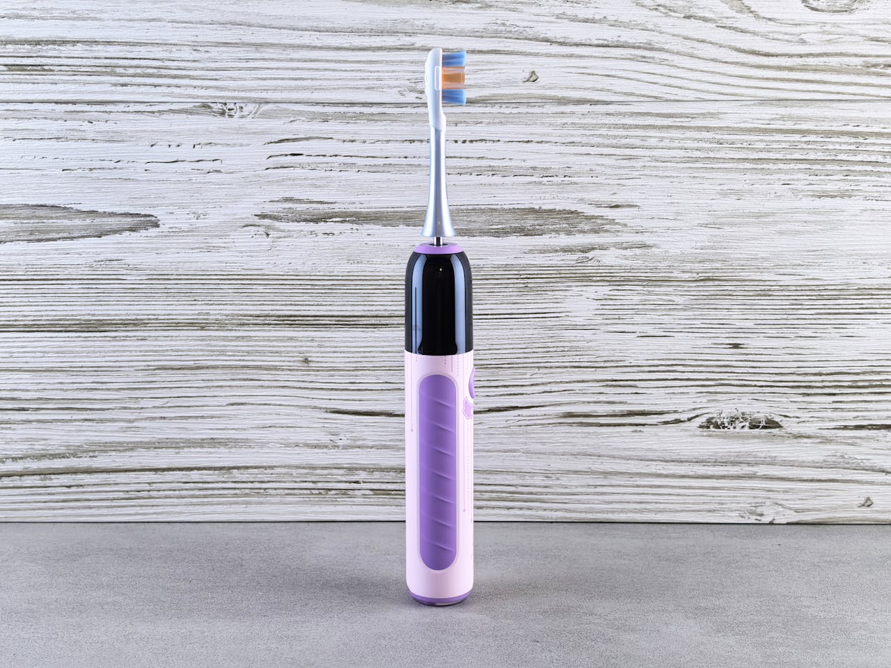 Purple electric toothbrush standing upright against a rustic wood background.